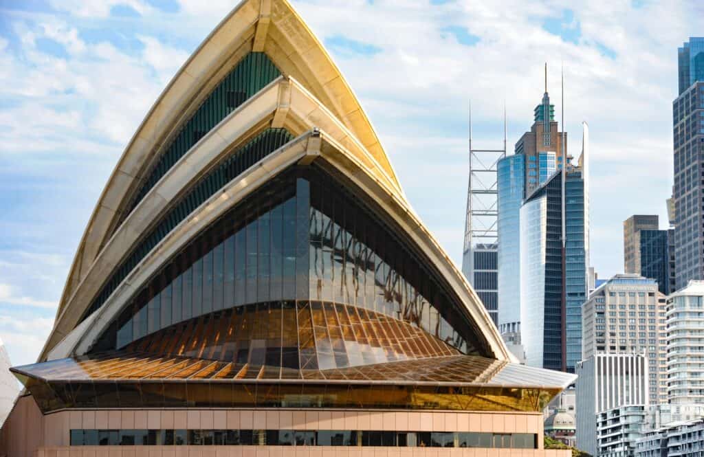 Sleek modern Sydney Opera House with city skyline in background.